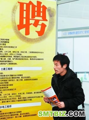 2月12日，舒杰从一家用人企业的招聘展台前走过。